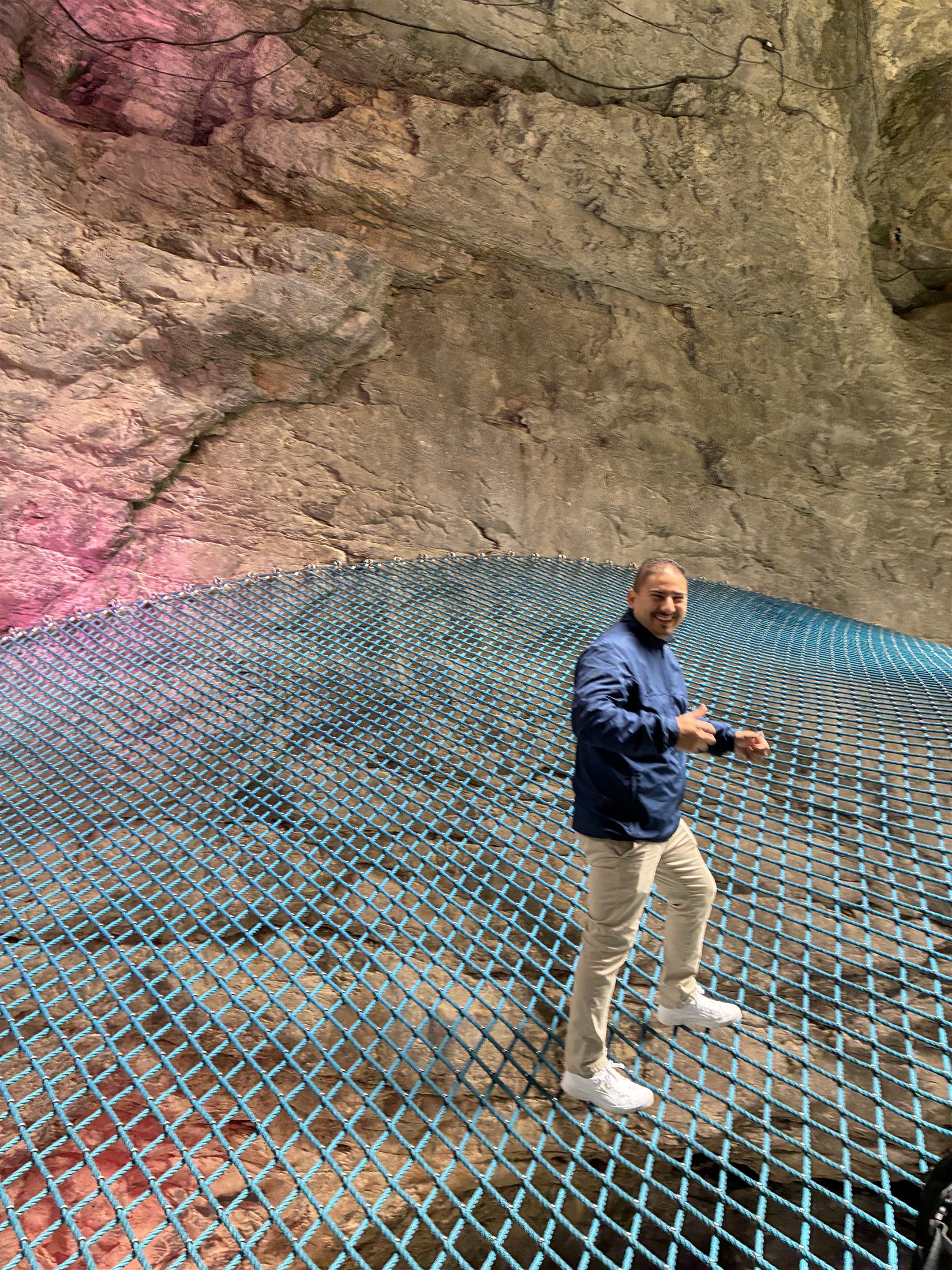 Visitante curvado sobre a rede azul suspensa no interior da garganta do glaciar de Grindelwald, entre paredes de rocha granítica