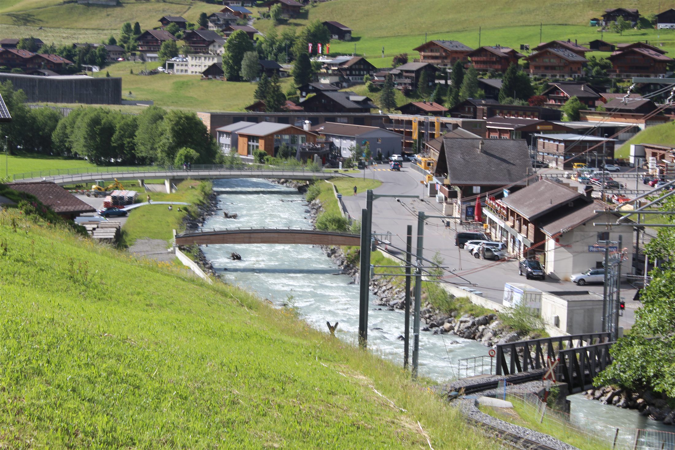 Área central de Grindelwald com o rio glacial Weisse Lütschine turquesa e a estação ferroviária