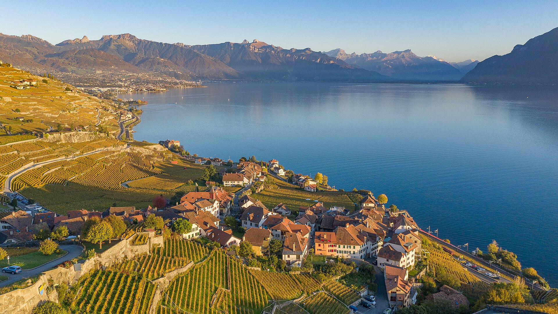 Os terraços de vinha de Lavaux descendo até o Lago Léman, com uma aldeia vinhateira e os Alpes ao fundo