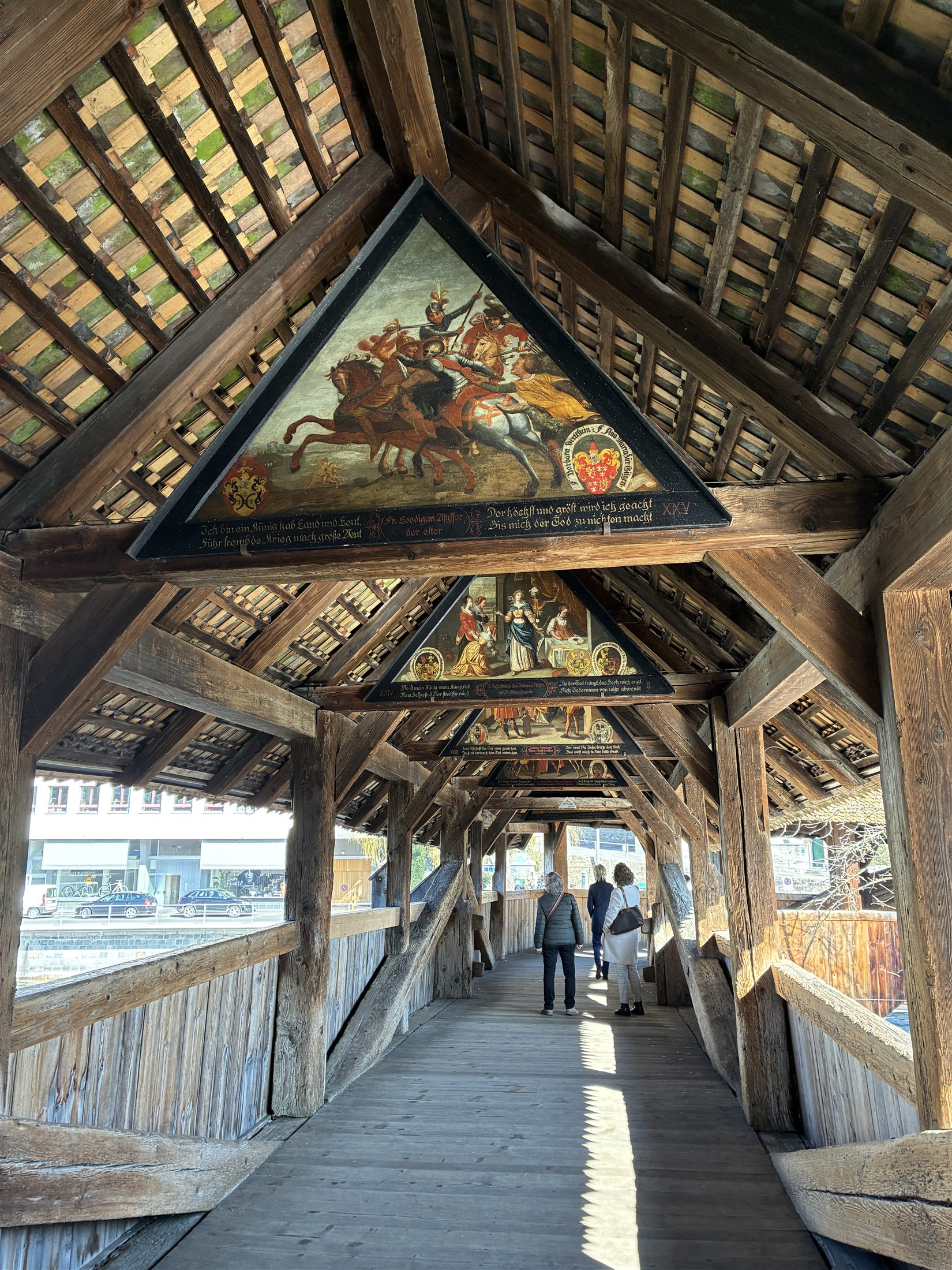 Interior da Kapellbrücke de Lucerna, um corredor de madeira com pinturas penduradas nas vigas do teto