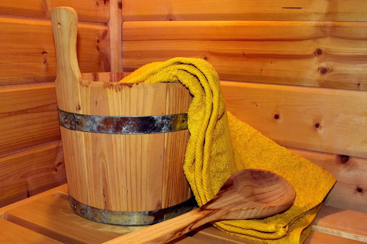 Balde de madeira, concha e toalha sobre o banco de uma sauna de madeira, o ritual clássico do banho de calor