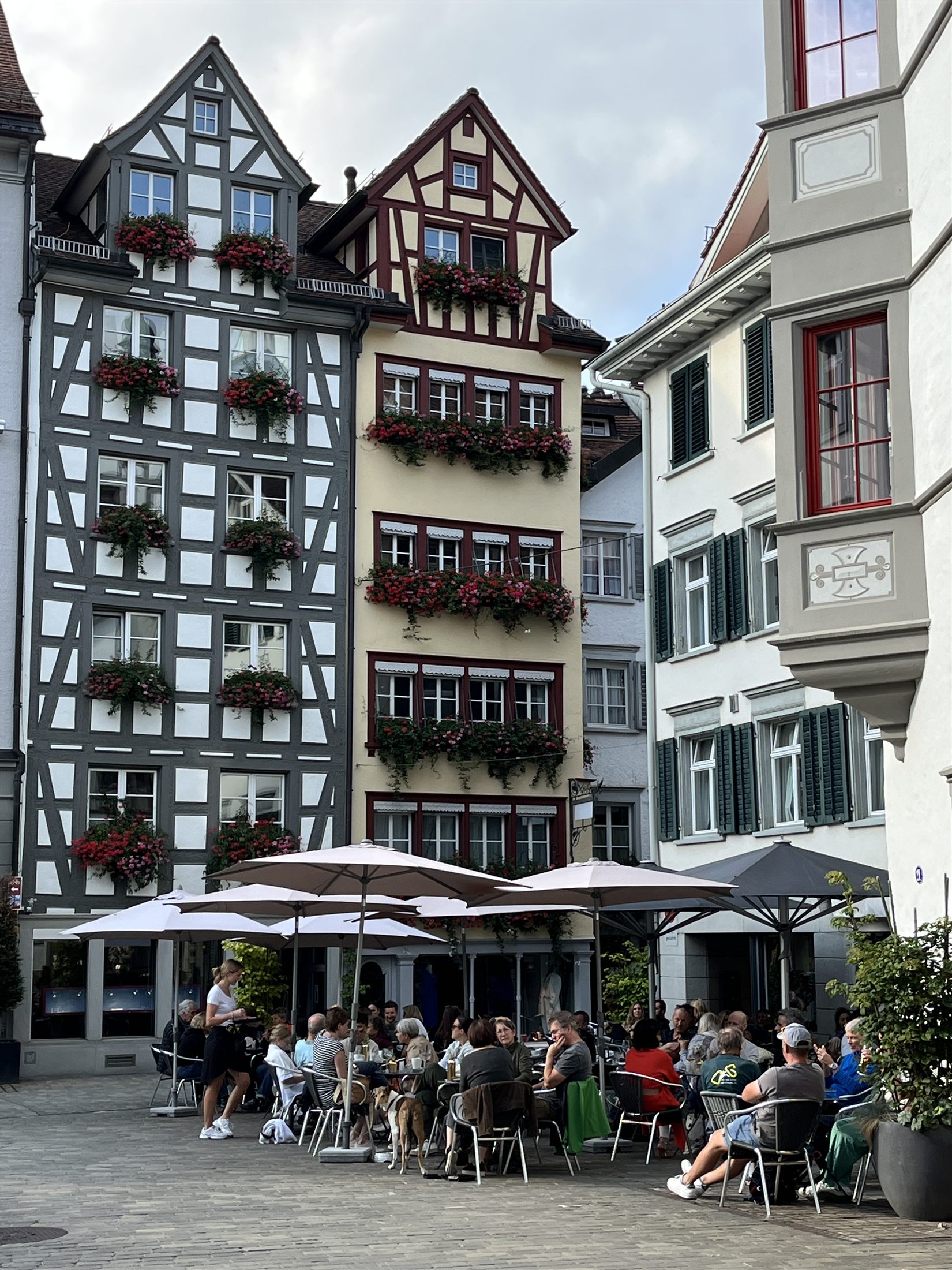 Edifícios históricos de enxaimel com flores vermelhas nas janelas em uma praça do centro histórico de São Galo