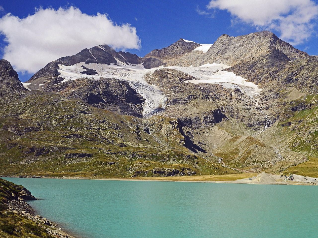 Ospizio Bernina a 2253 metros com o Lago Bianco de água leitosa pelo sedimento glacial nos Alpes de Graubünden