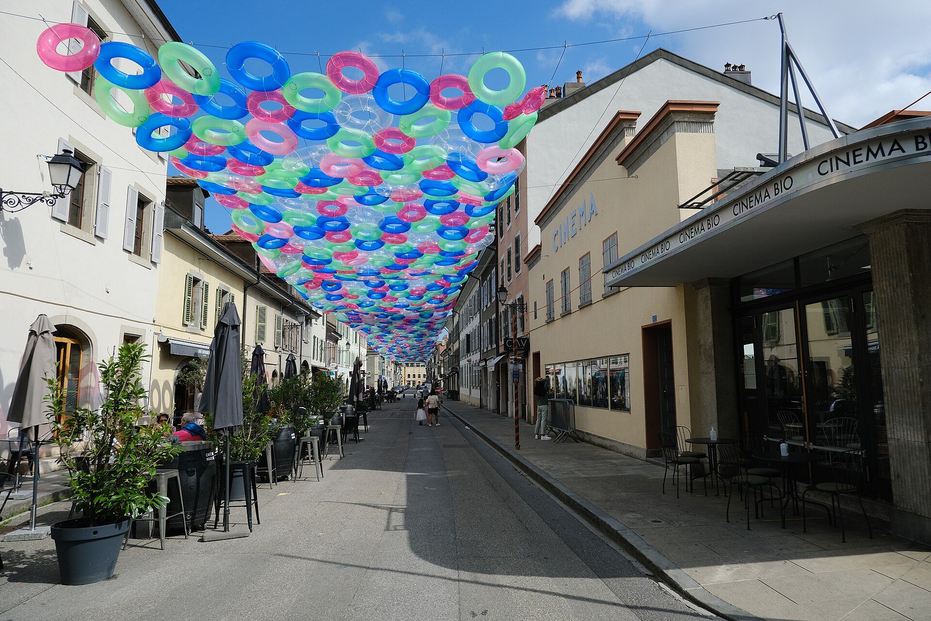 Rua de Carouge com fachadas sardenhas coloridas e terraços de café, em Genebra