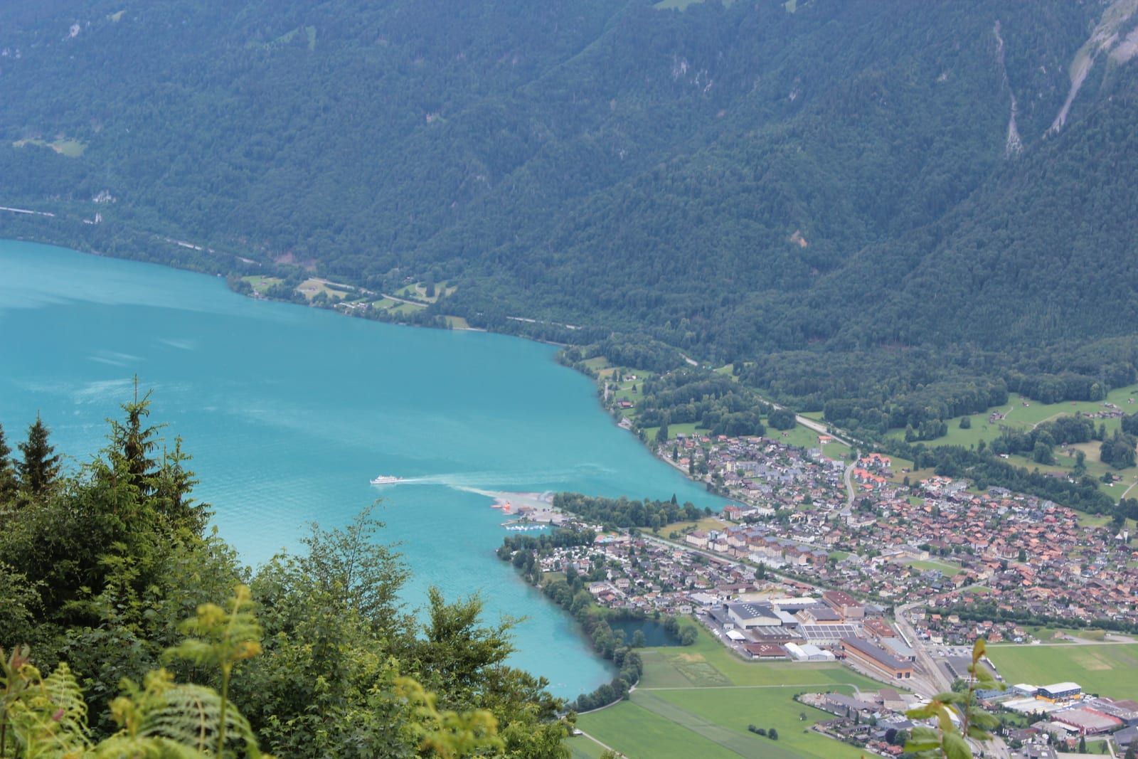 O Lago de Brienz, de água esmeralda, com um barco de passageiros e montanhas ao redor