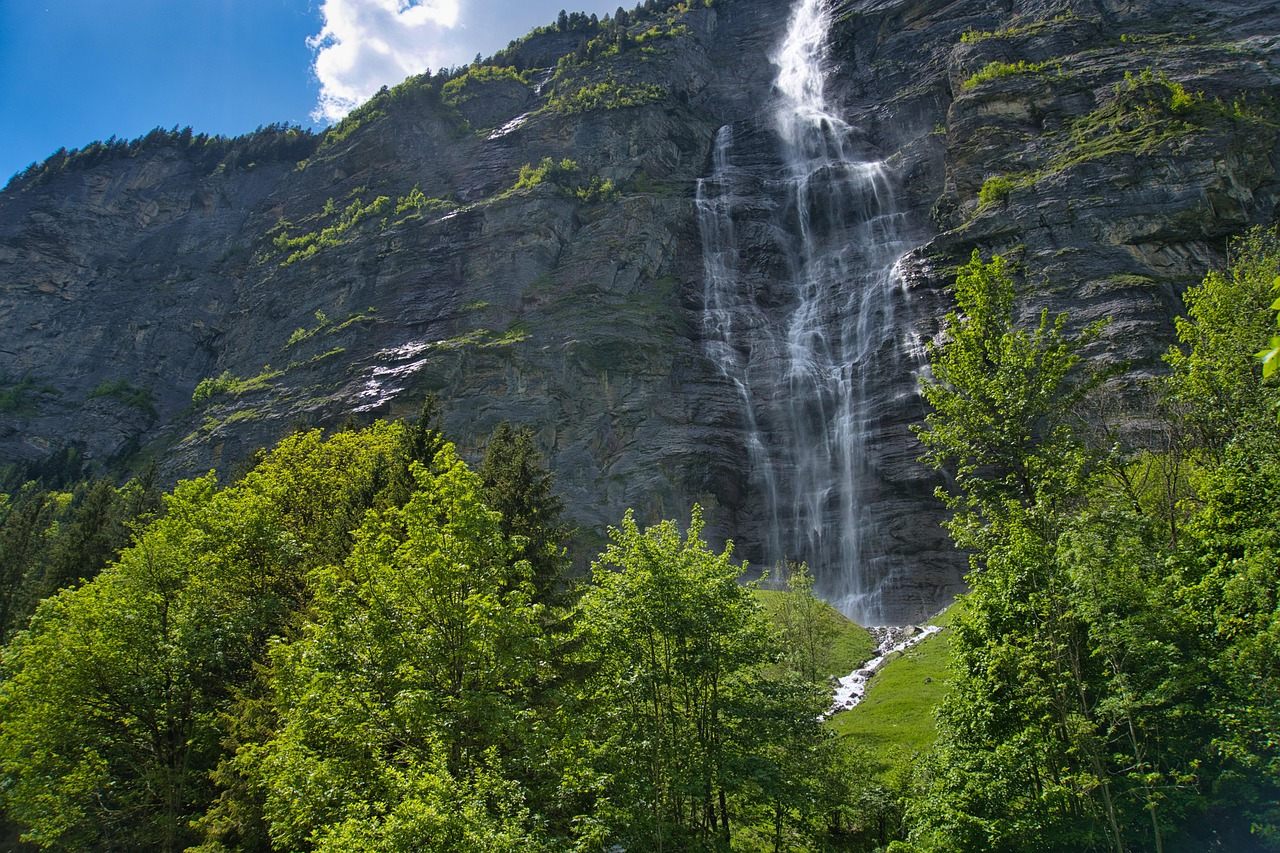 Trilha plana do Vale de Lauterbrunnen com cachoeiras nas paredes laterais e o rio Weisse Lütschine ao lado