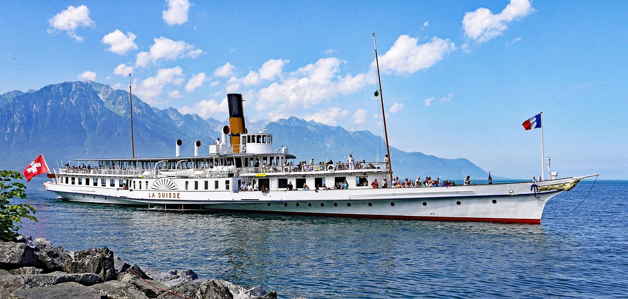 O barco a vapor histórico La Suisse navegando no Lago Léman, com os Alpes ao fundo