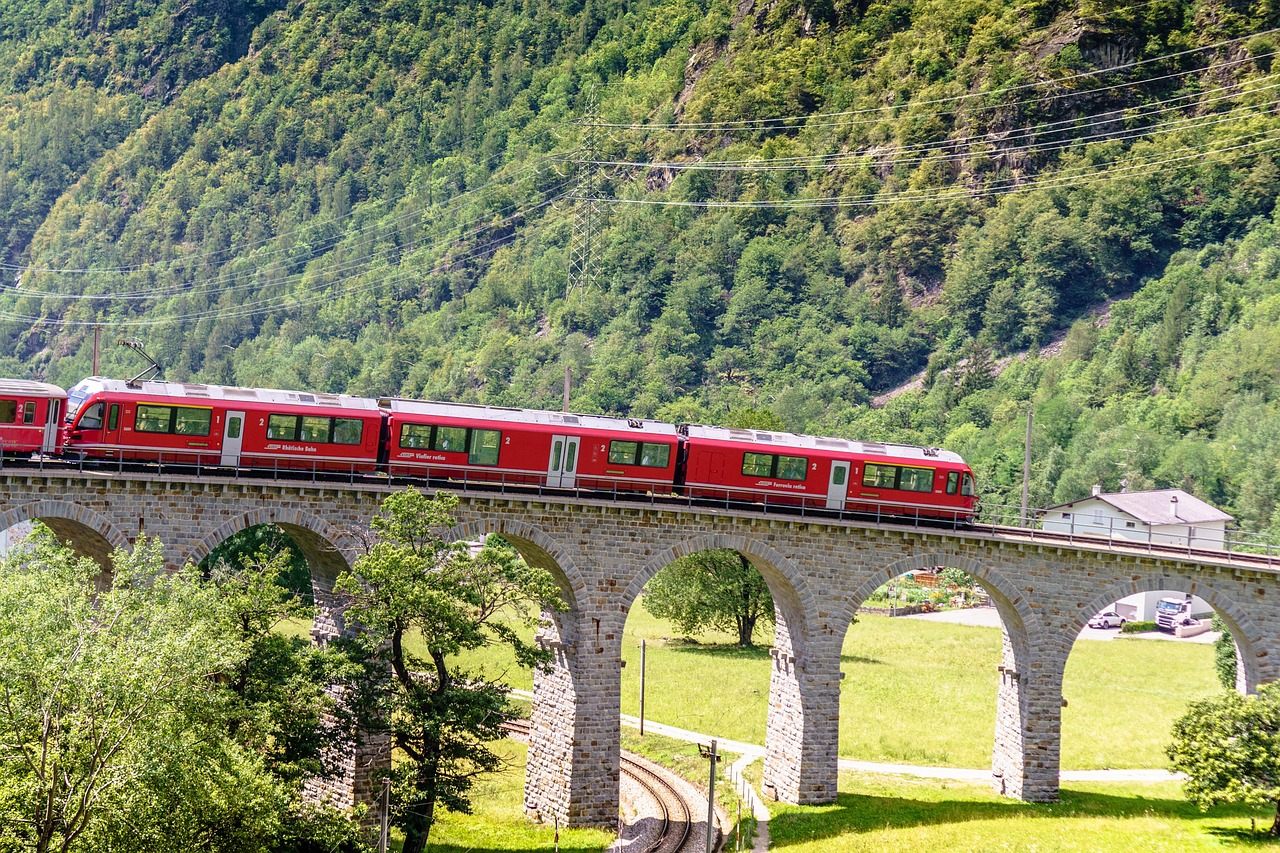 Trem vermelho da Ferrovia Rética cruzando um viaduto na rota panorâmica do Glacier Express