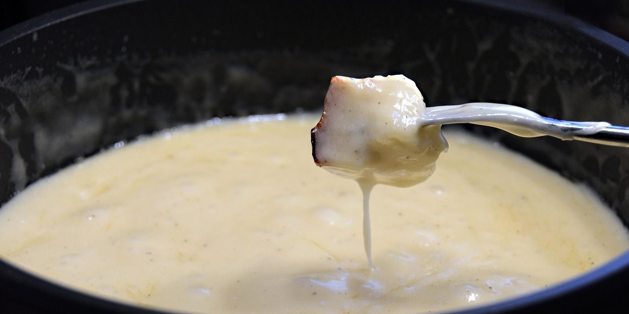 Fondue de queijo suíço, prato típico servido em panela sobre a mesa