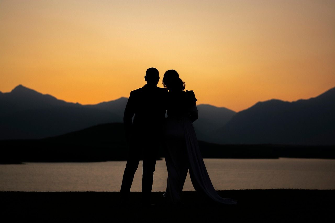 Silhueta de um casal ao entardecer diante de um lago e montanhas, em uma cena romântica na Suíça