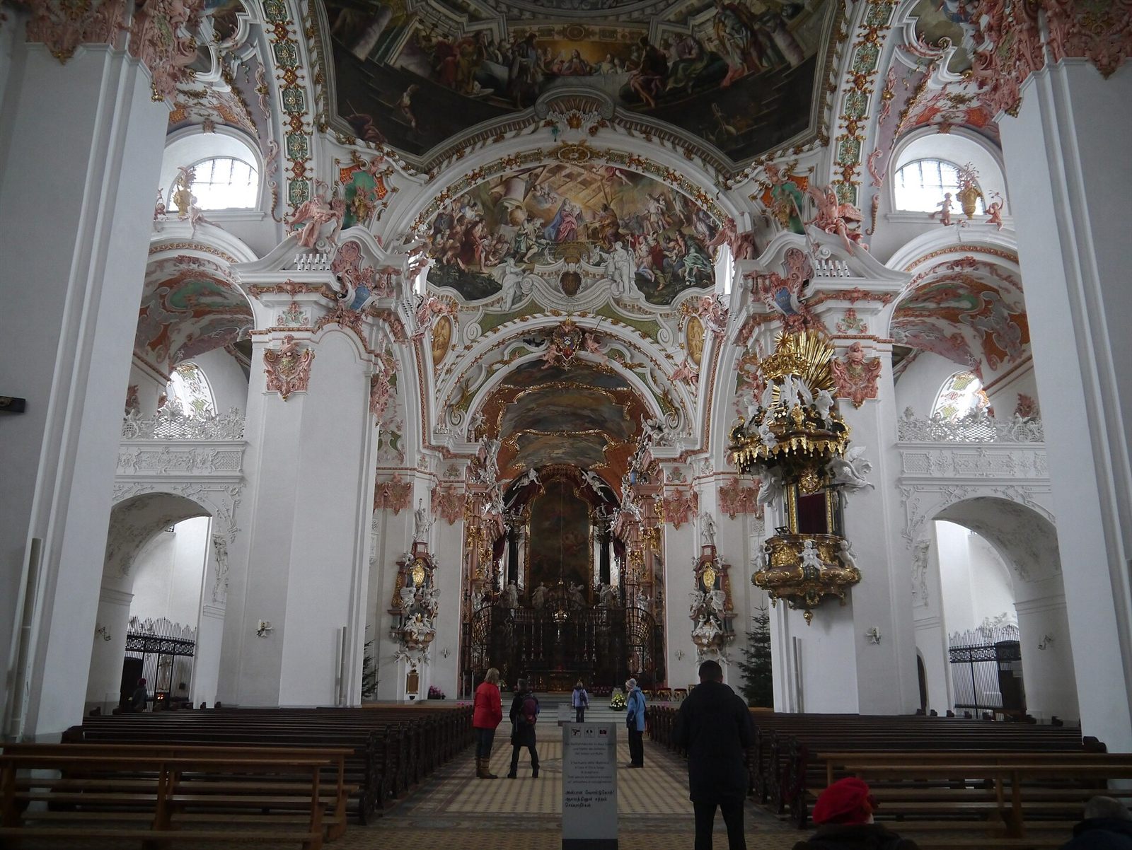 Nave central da igreja abacial barroca de Einsiedeln em direção ao altar-mor, com bancos de madeira