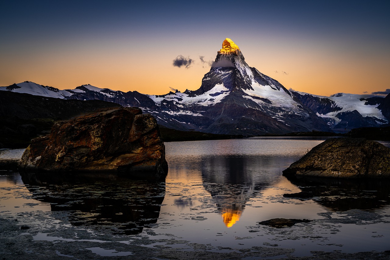 O Matterhorn ao amanhecer, com o cume dourado refletido em um lago de altitude perto do Gornergrat, no Valais