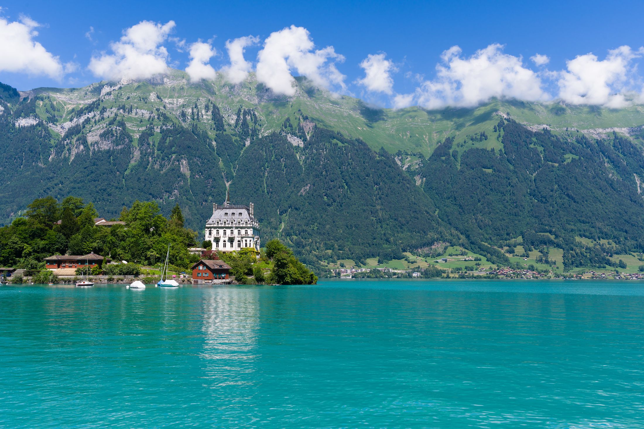 Água turquesa do Lago de Brienz vista do convés de um barco, cor criada pelas partículas glaciais com as cataratas de Giessbach ao fundo, Interlaken