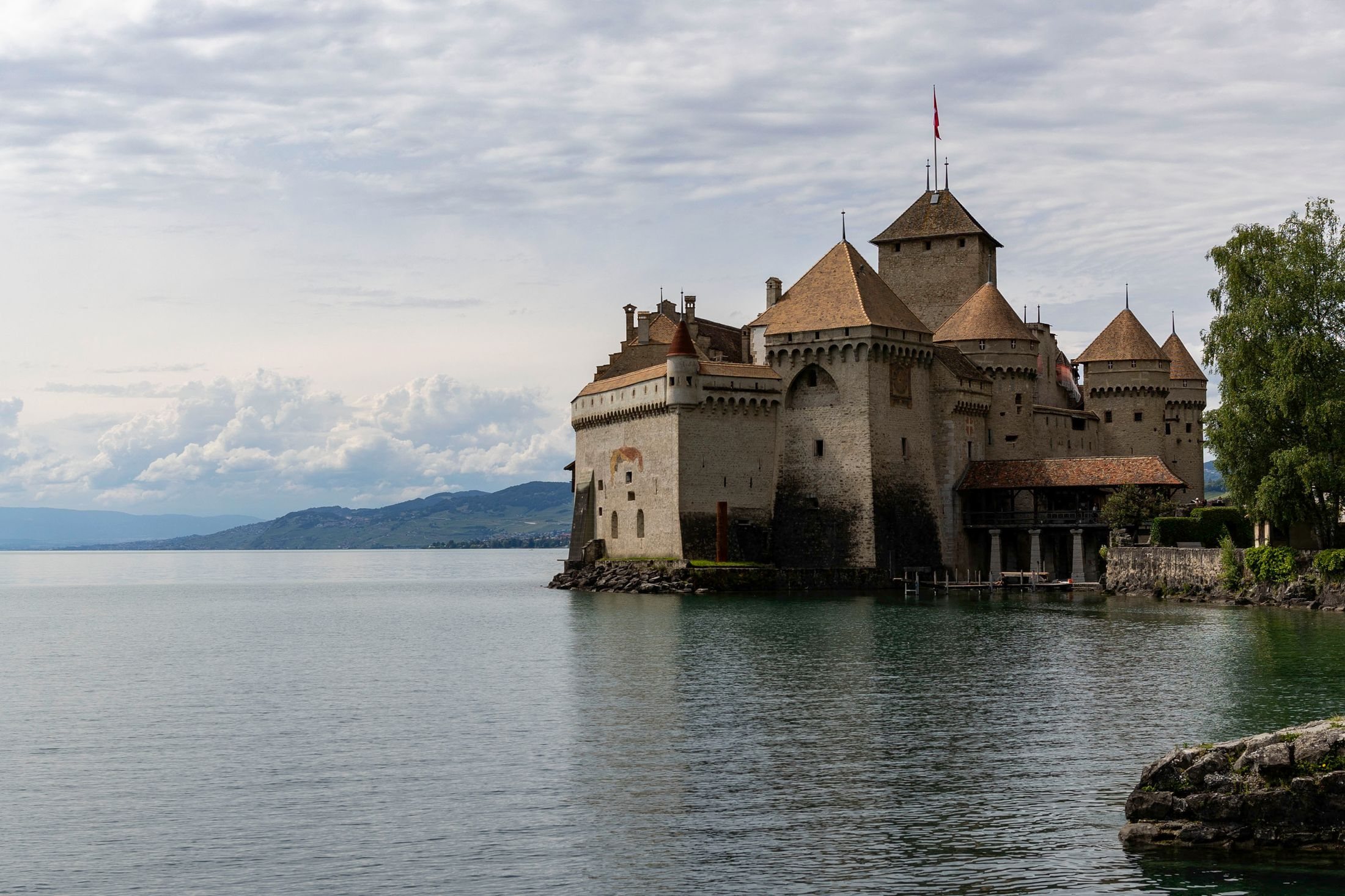 Castelo de Chillon visto da água do Lago Genebra, fortaleza medieval do século XII que parece flutuar na margem em Veytaux, Suíça