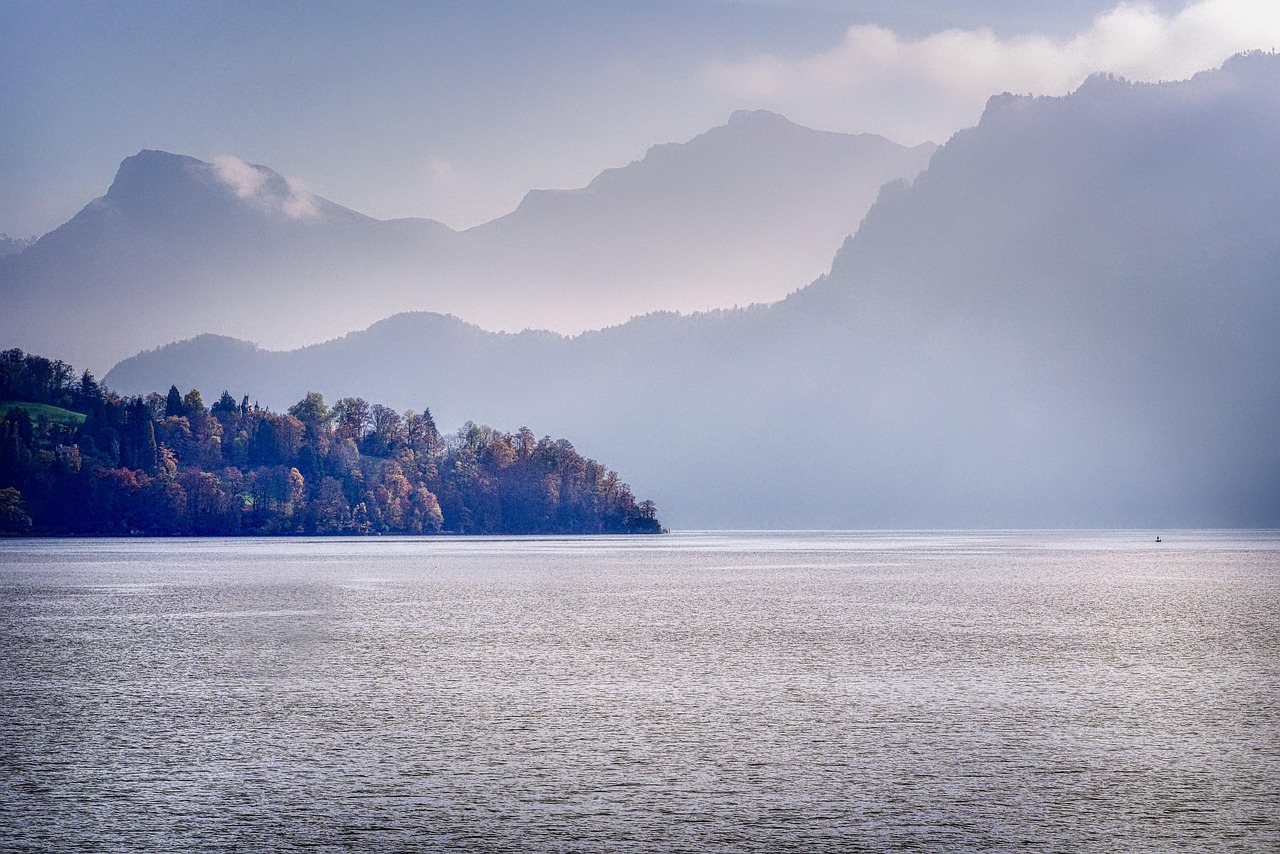 Vapor de roda da SGV no Lago de Lucerna ao amanhecer, névoa matinal sobre a água com as montanhas dos quatro cantões ao fundo