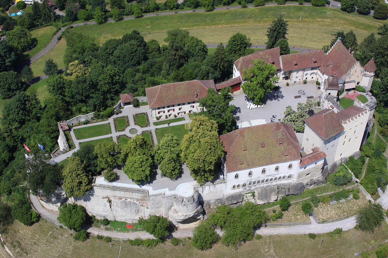 Vista aérea do Schloss Lenzburg, no Aargau, com pátios, jardins e telhados vermelhos sobre a colina