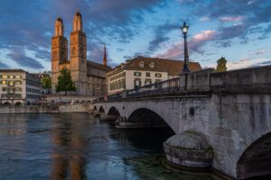 O Grossmünster e a Münsterbrücke sobre o rio Limmat ao entardecer, na Altstadt de Zurique