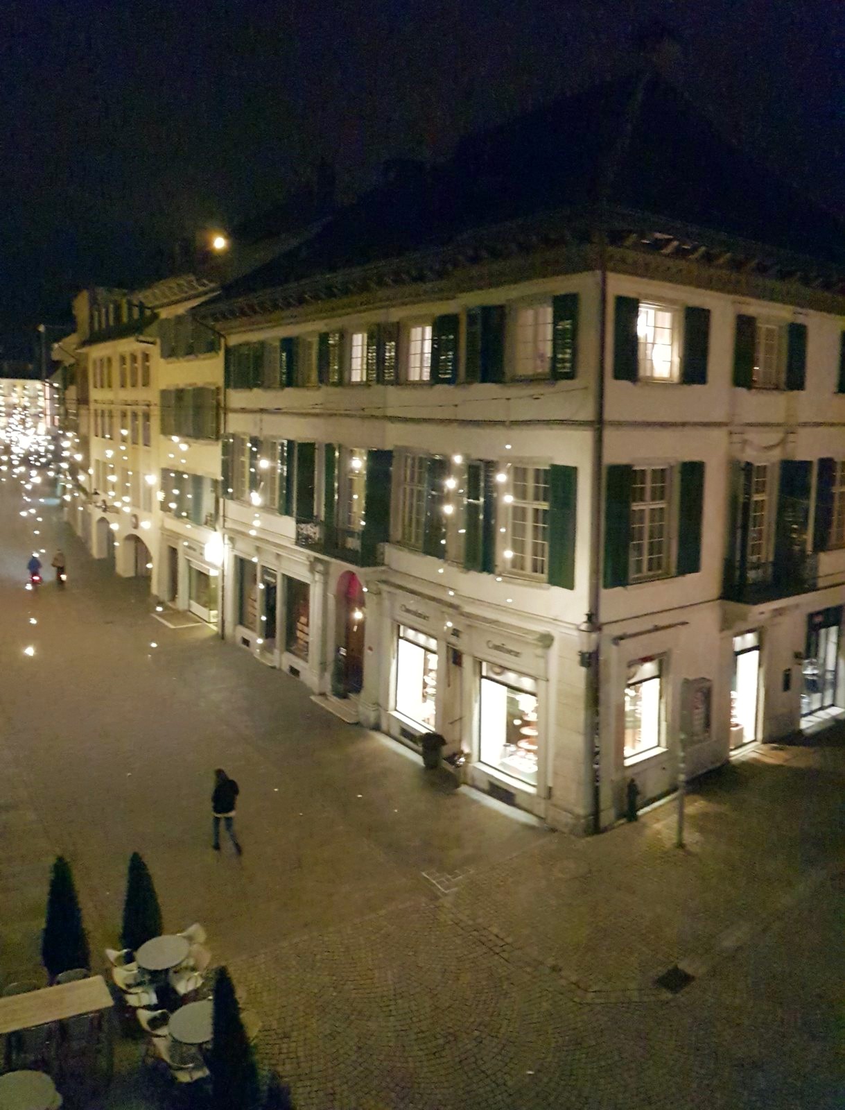 Rua da cidade velha de Solothurn à noite, com vitrines acesas e luzes de Advento