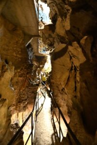 Desfiladeiro estreito dentro das Grutas de São Beatus com passarela de madeira suspensa e visitantes ao fundo