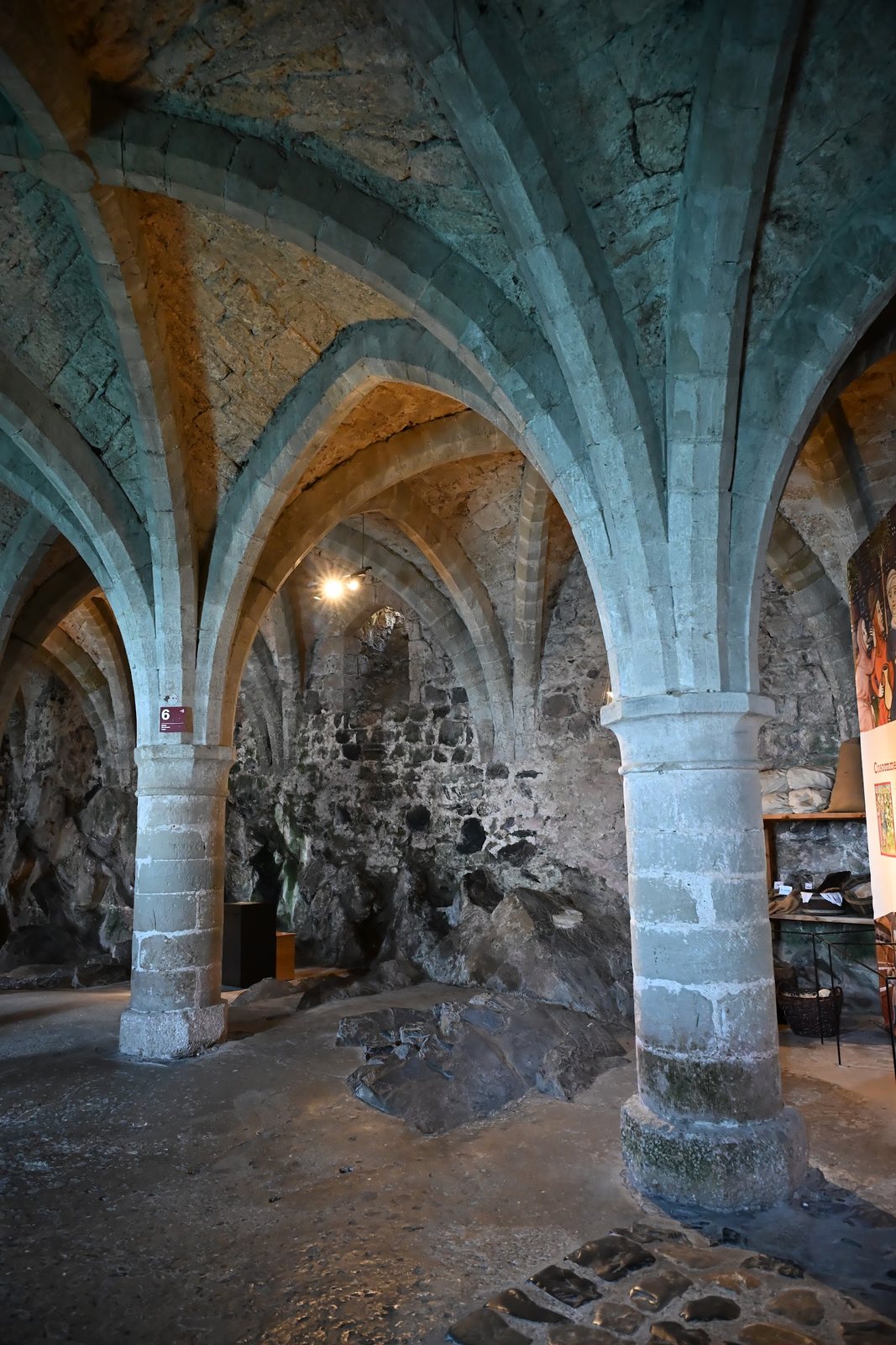 Abóbadas góticas e a rocha da ilha aparecendo na parede dos subterrâneos do Castelo de Chillon