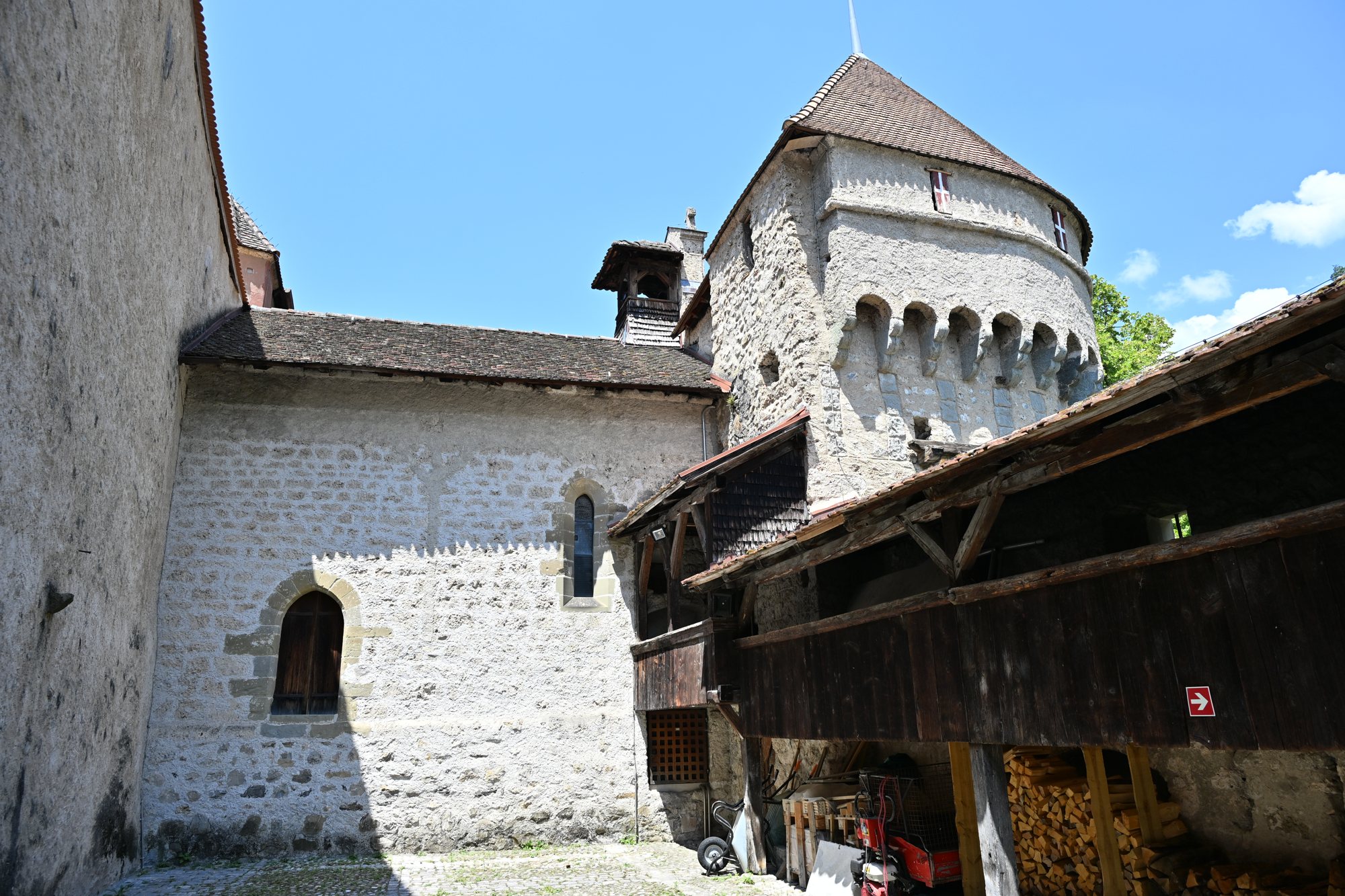 Adarves de madeira sobre a muralha do Castelo de Chillon, com torres cônicas e a bandeira da cruz de Saboia