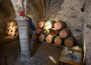 Barris do Clos de Chillon empilhados na adega do Castelo de Chillon, com pilar de pedra e vitrine com a garrafa