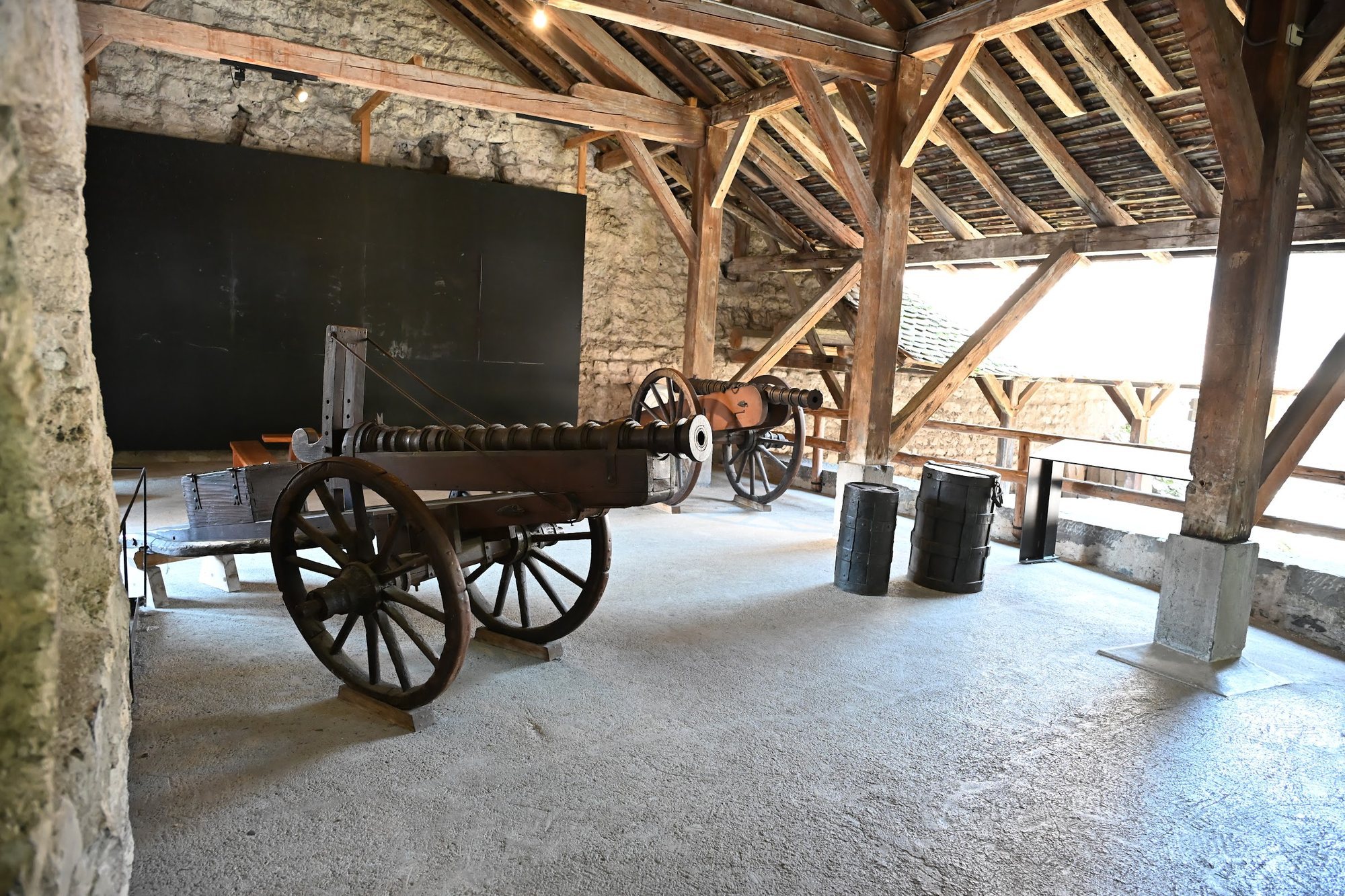 Duas peças de artilharia sobre carreta, barris de pólvora e um carro de quatro rodas sob a galeria de madeira do Castelo de Chillon
