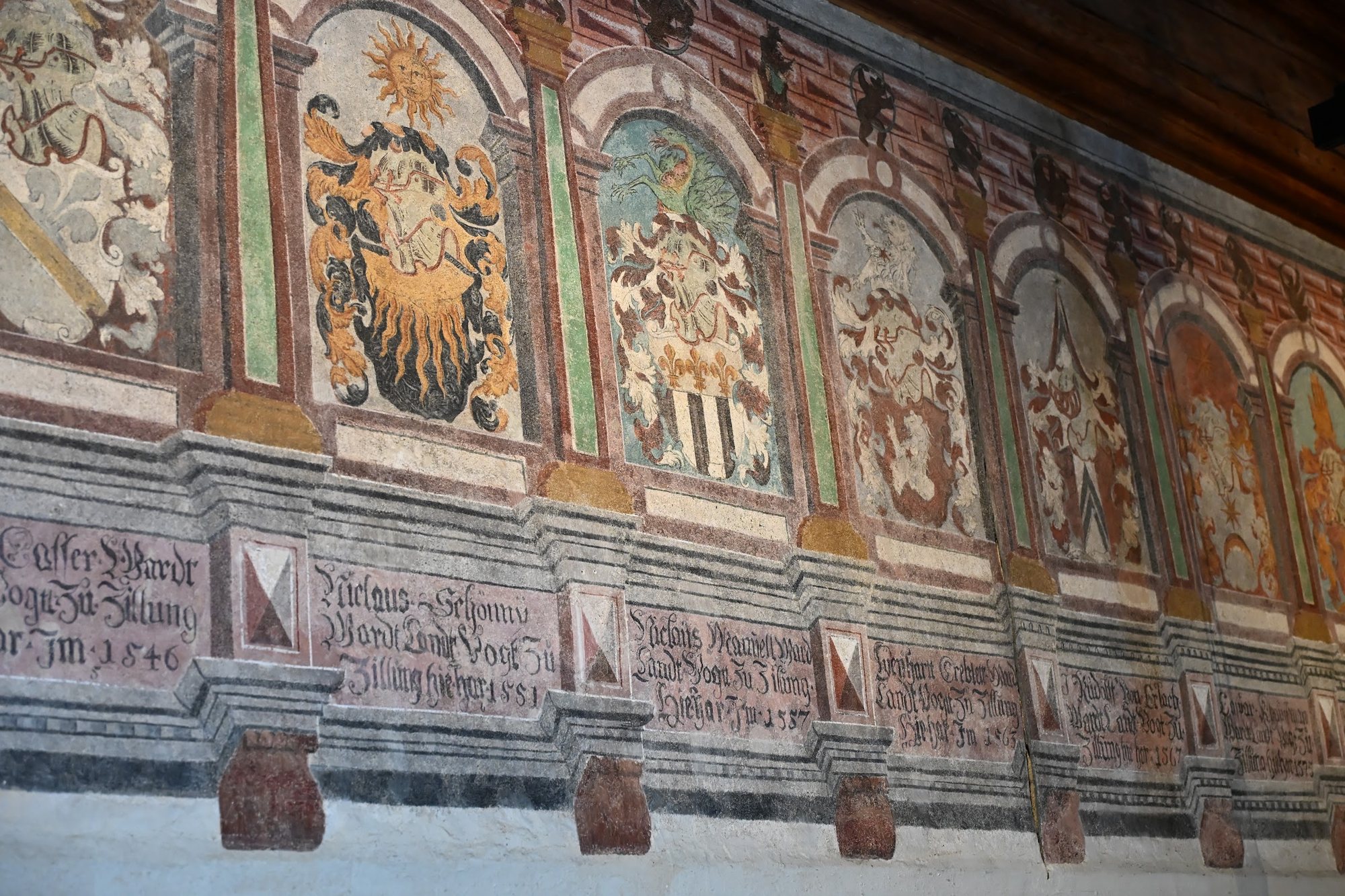 Friso de armas dos bailios berneses no Castelo de Chillon, com cimeiras, arquitetura pintada em grisalha e inscrições góticas datadas de 1546 a 1567