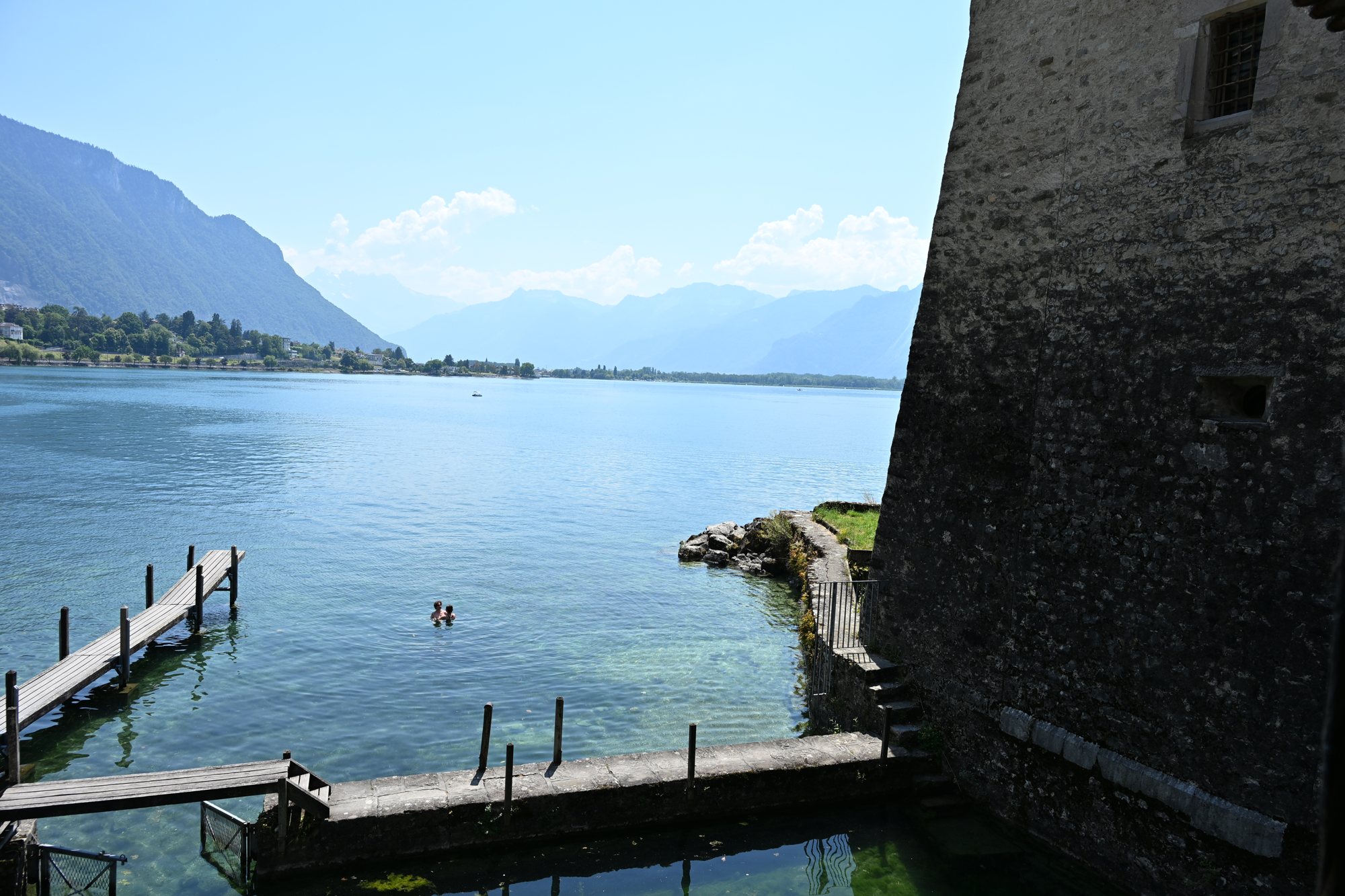 Píer de madeira ao lado da muralha do Castelo de Chillon, com o Lago Léman e as montanhas do Chablais