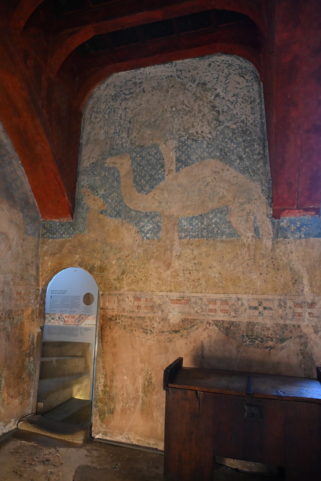 Detalhe da camera domini de Chillon com um animal de pescoço longo pintado sobre fundo de flores-de-lis, sob viga vermelha