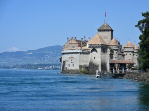 Castelo de Chillon sobre a ilha de rocha no Lago Léman, com a fachada do lago coroada de matacães