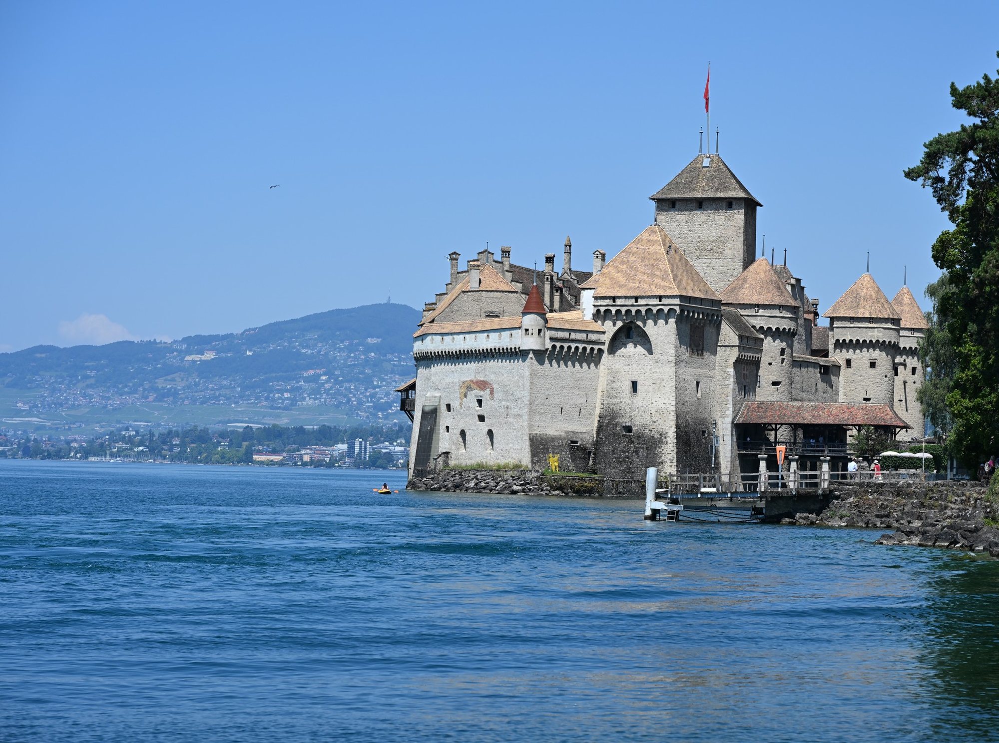 Castelo de Chillon sobre a ilha de rocha no Lago Léman, com a fachada do lago coroada de matacães