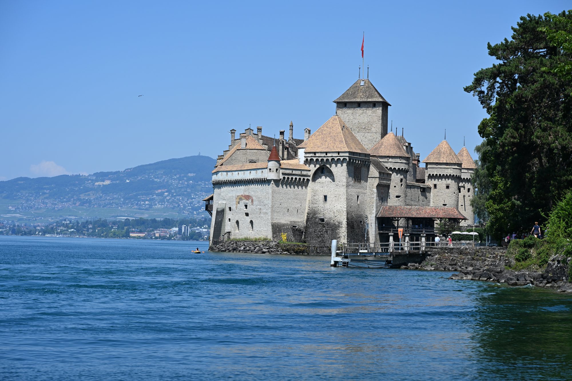 Castelo de Chillon sobre a ilha de rocha, com o Lago Léman à frente e a encosta de Montreux ao fundo