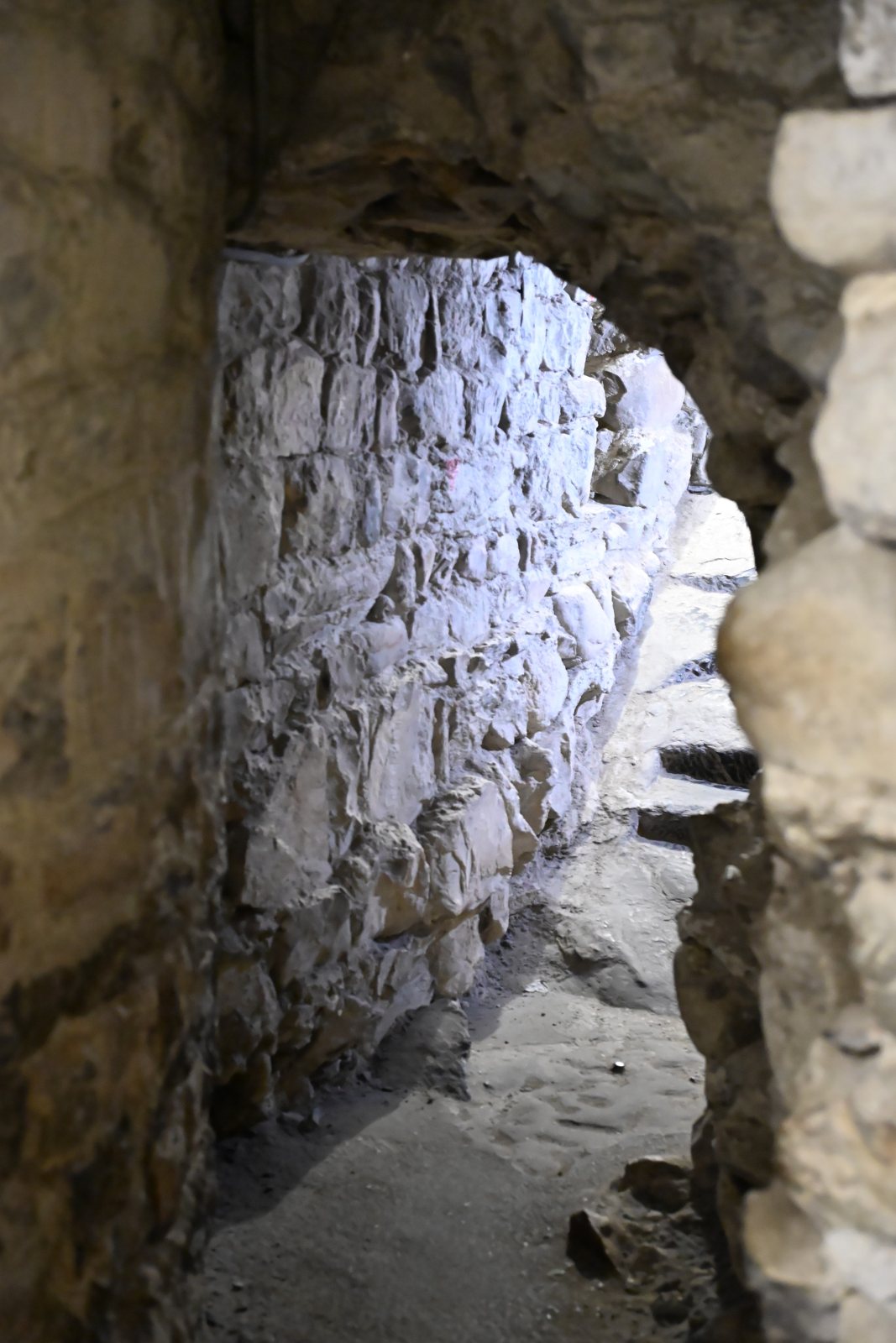 Passagem estreita de pedra entre as muralhas do Castelo de Chillon, com o chão irregular