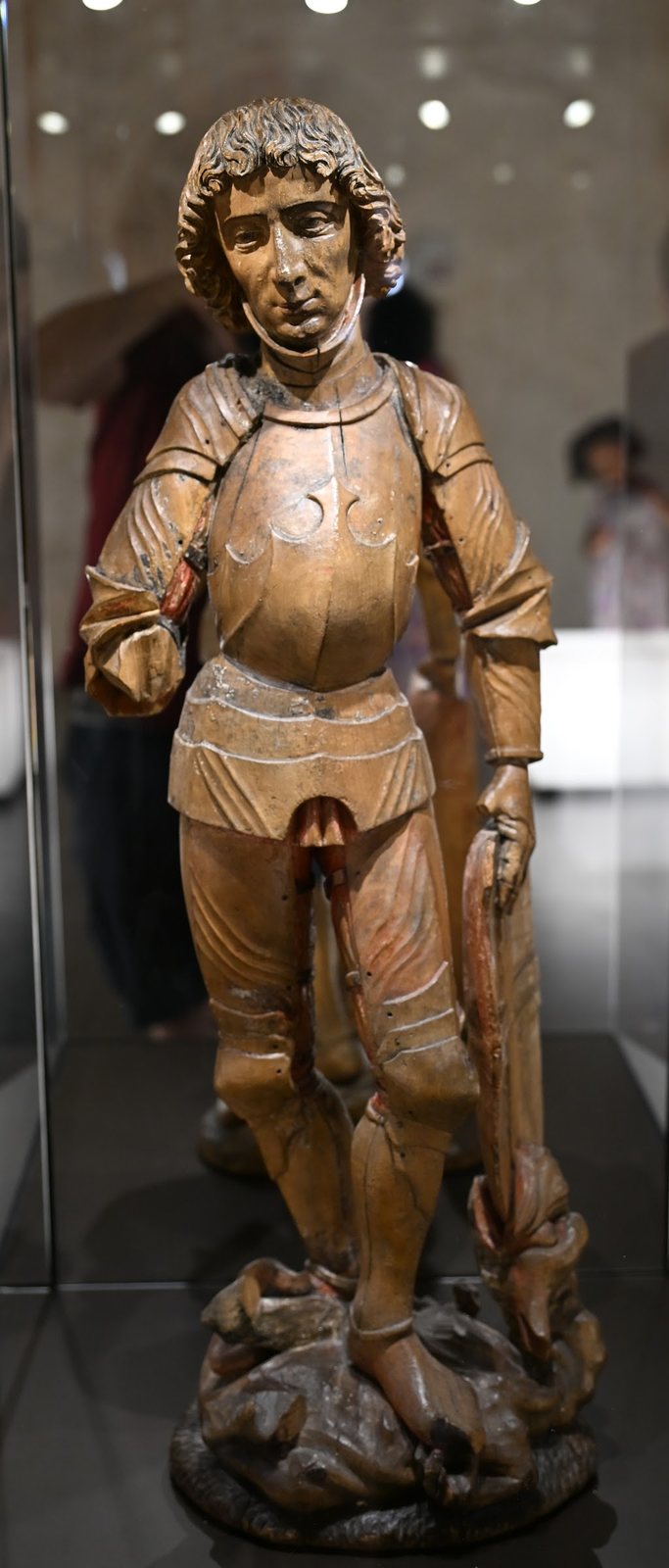 Estátua de madeira de são Jorge em armadura sobre o dragão, exposta em vitrine na capela do Castelo de Chillon