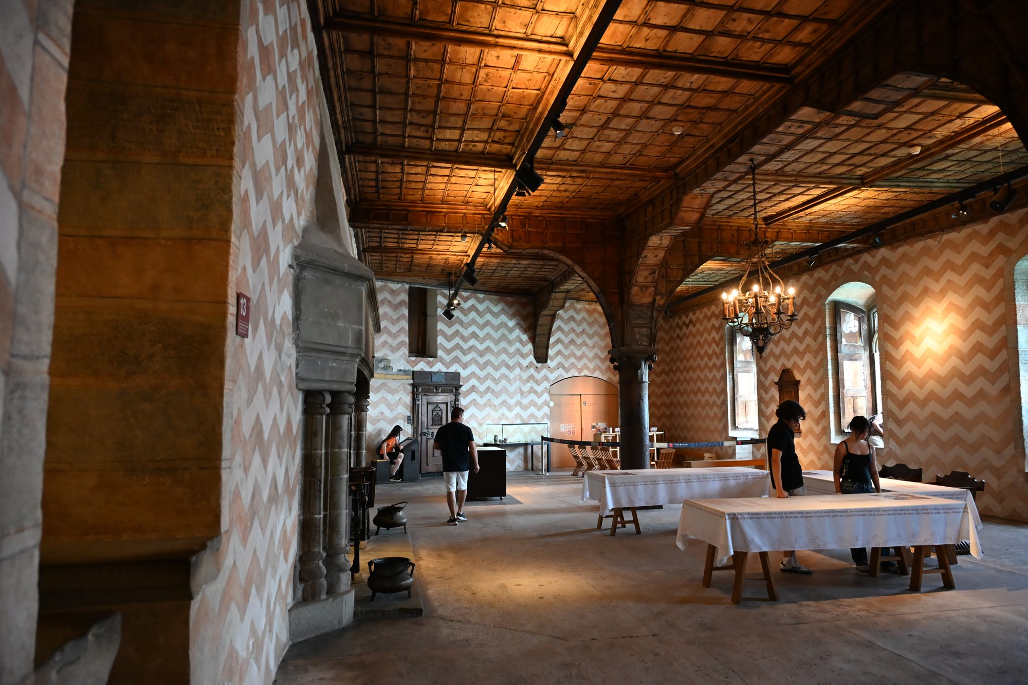 Grande sala do Castelo de Chillon com paredes pintadas em chevrons e teto de madeira