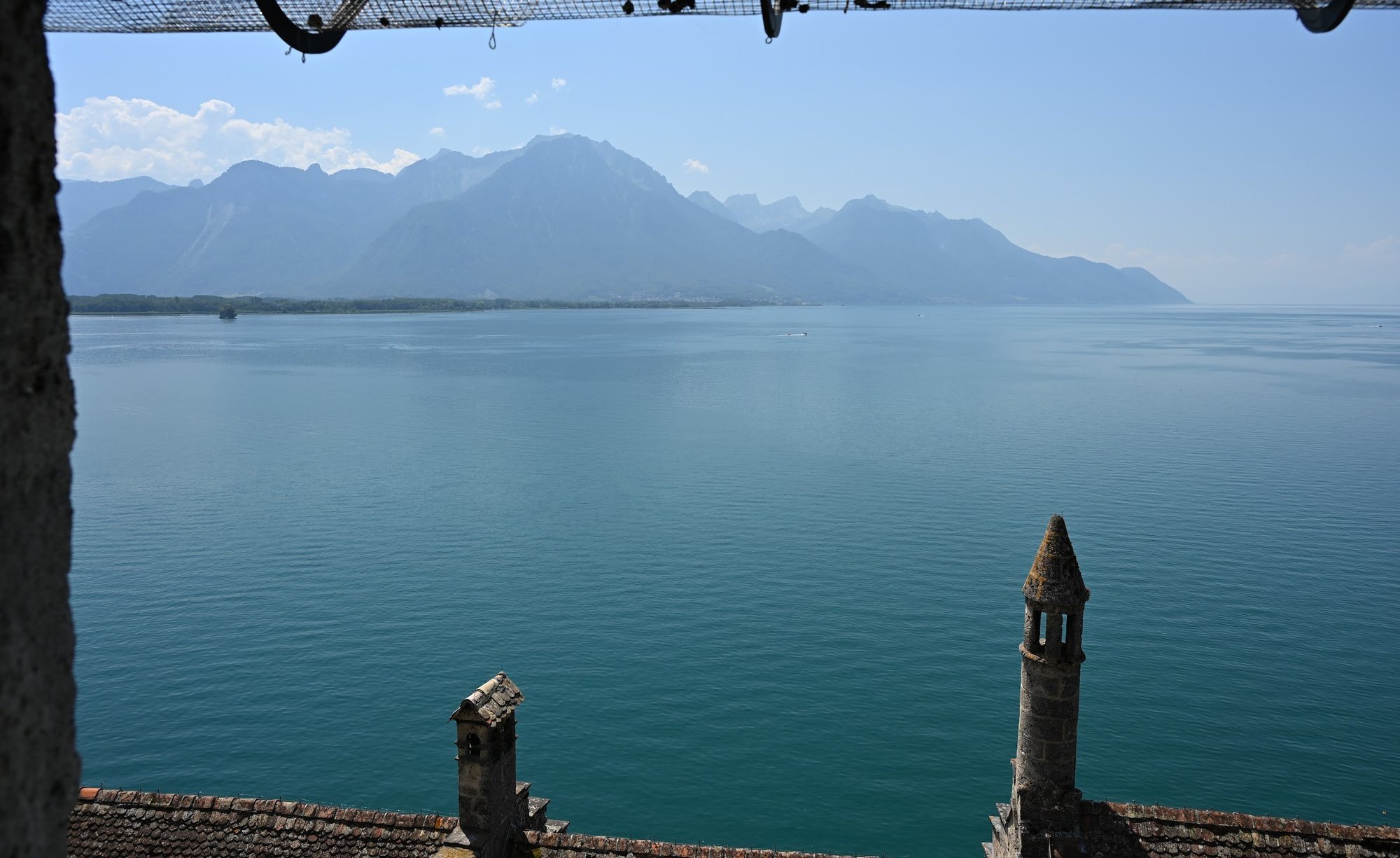 Vista do alto do Castelo de Chillon para sudeste, com as chaminés do castelo, a planície do Ródano à esquerda e as montanhas do Chablais do outro lado da água