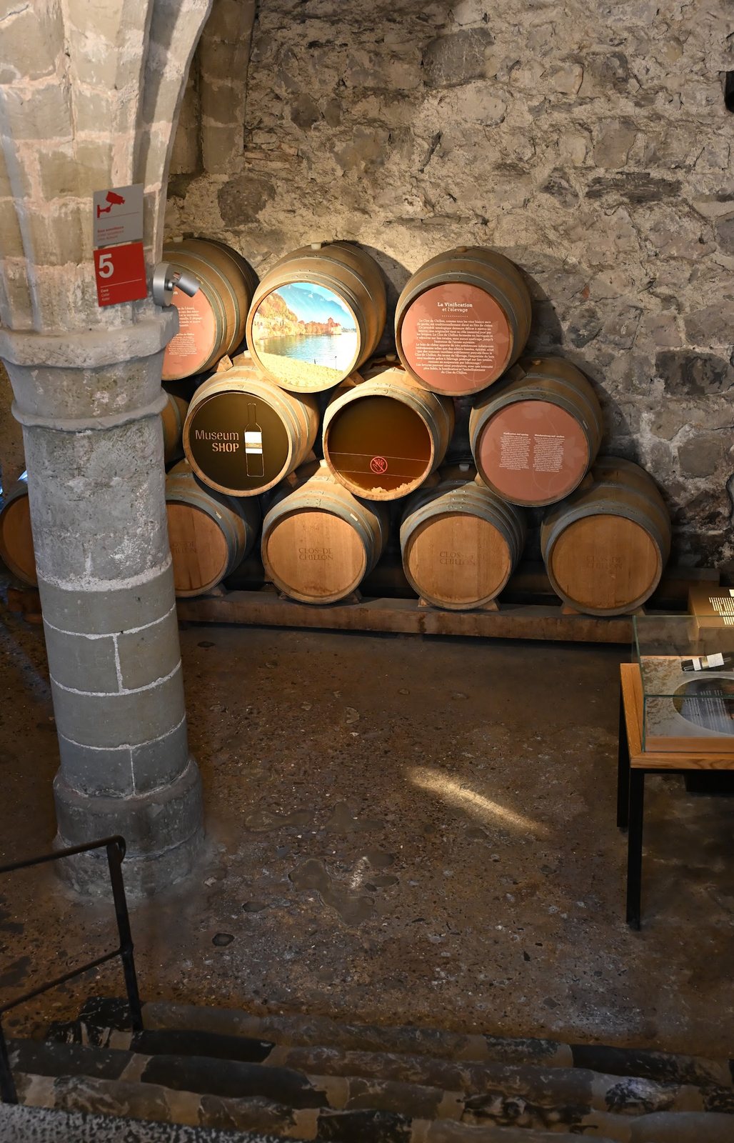 Barris do Clos de Chillon empilhados na primeira adega do Castelo de Chillon, com topos pintados, pilar gótico e a rocha da ilha