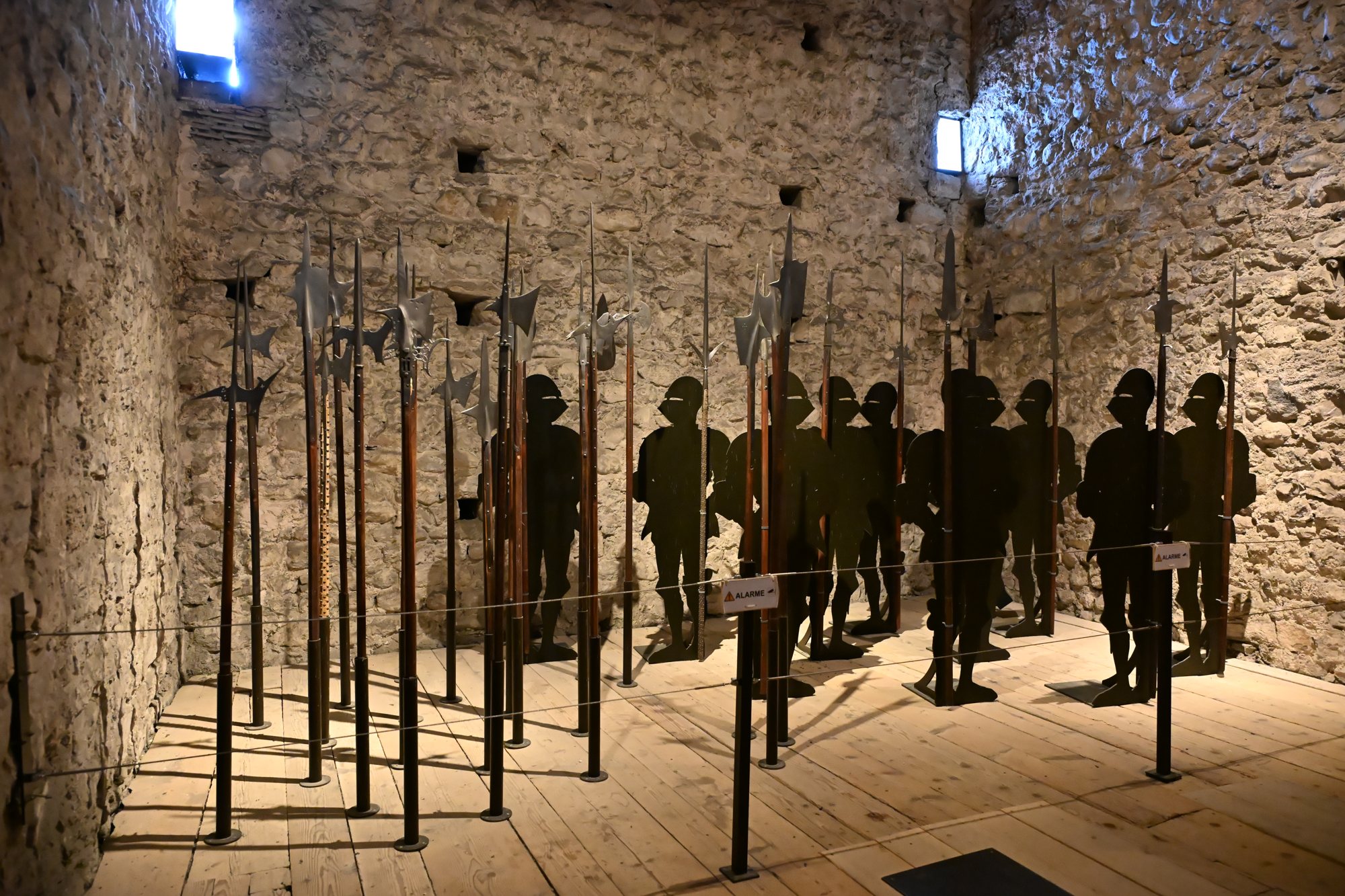 Sala de armas na torre de menagem de Chillon, com alabardas e silhuetas de soldados
