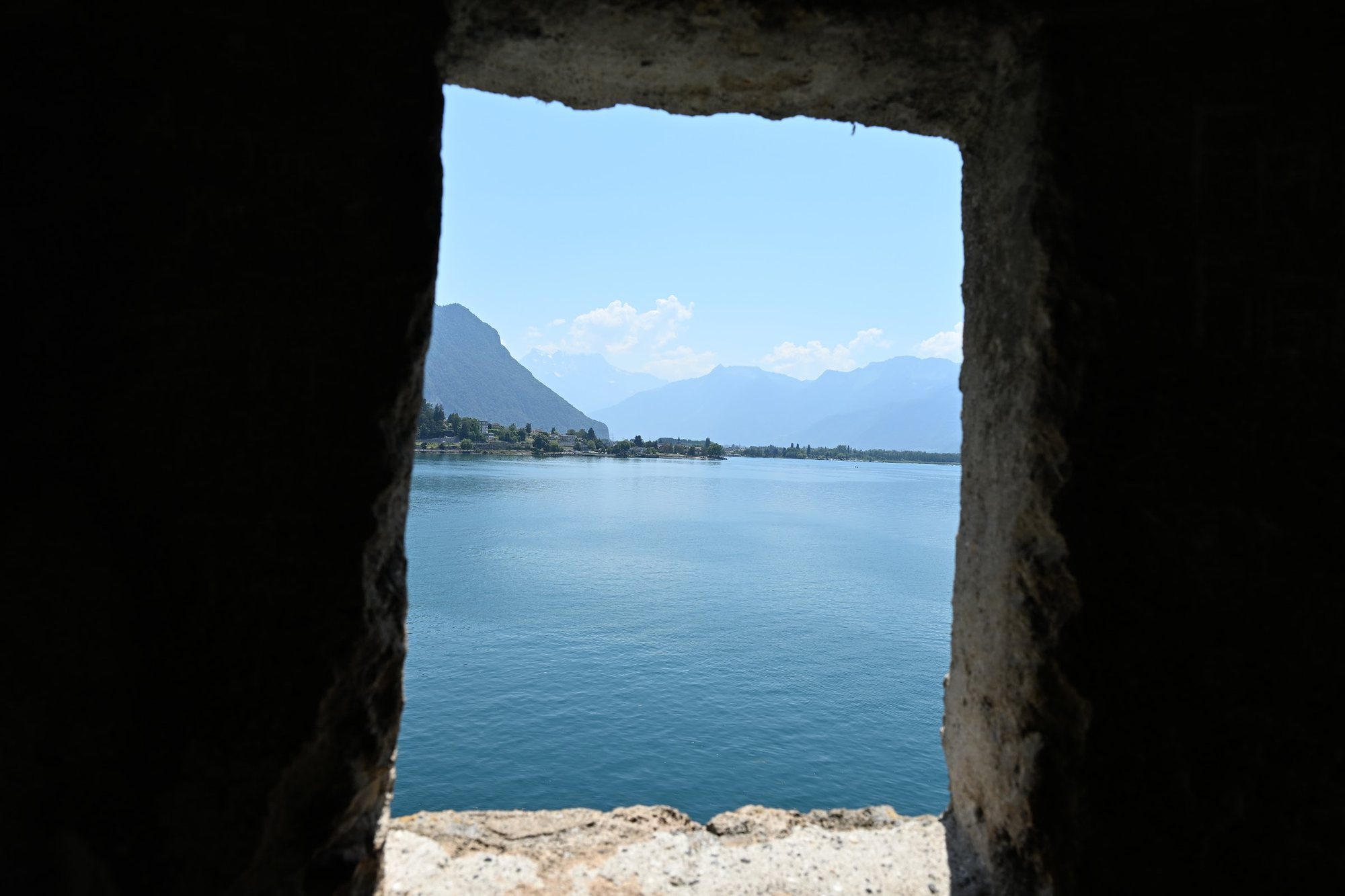 Seteira estreita do Castelo de Chillon emoldurando o azul do Lago Léman e a montanha do outro lado