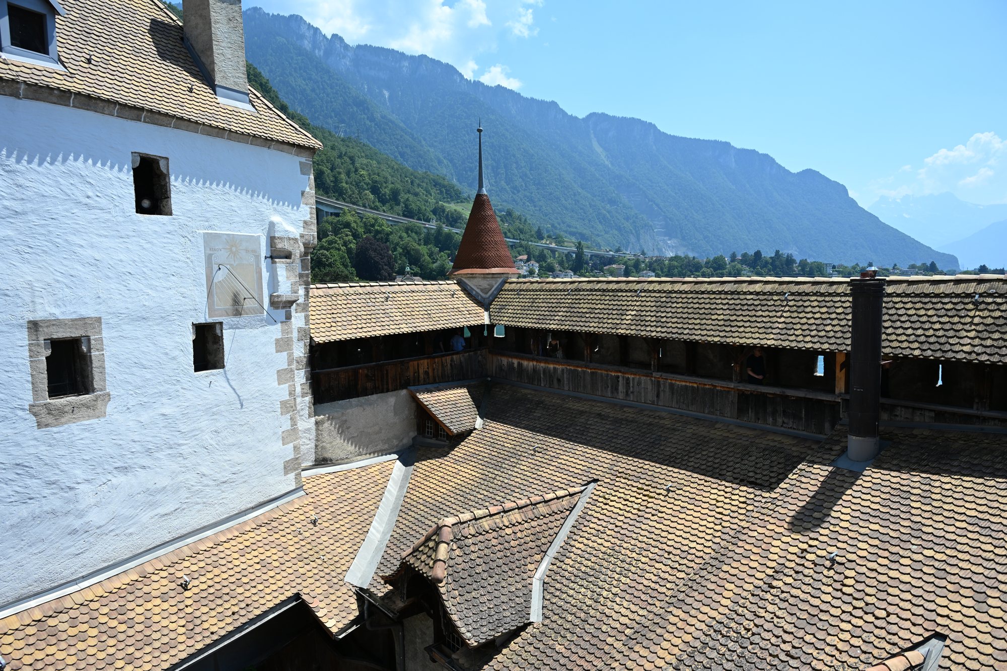 Telhados de barro do Castelo de Chillon vistos do alto, com a galeria coberta e as montanhas ao fundo
