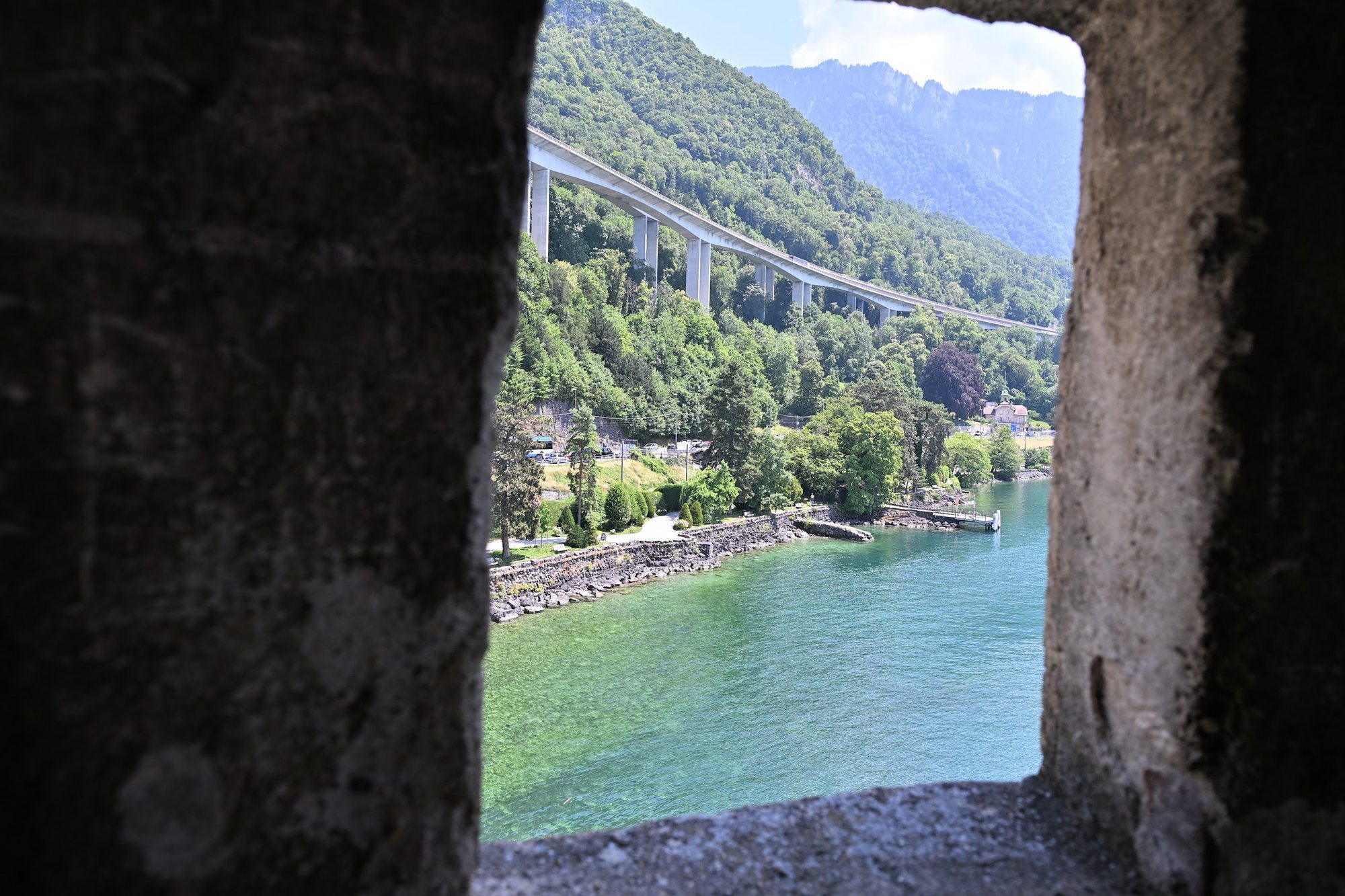 Viaduto da autoestrada A9 cruzando a encosta verde acima da orla de Veytaux, com a água esverdeada do Lago Léman abaixo