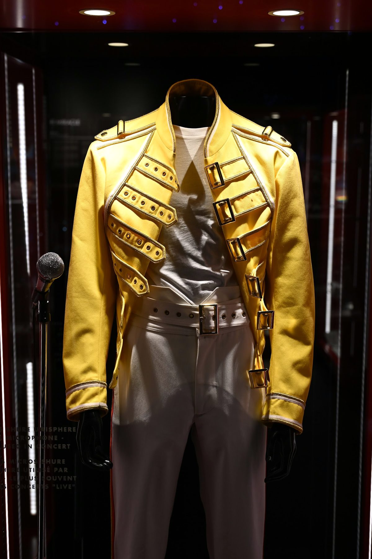 Jaqueta amarela de estilo militar e microfone Shure em vitrine na exposição do Queen em Montreux