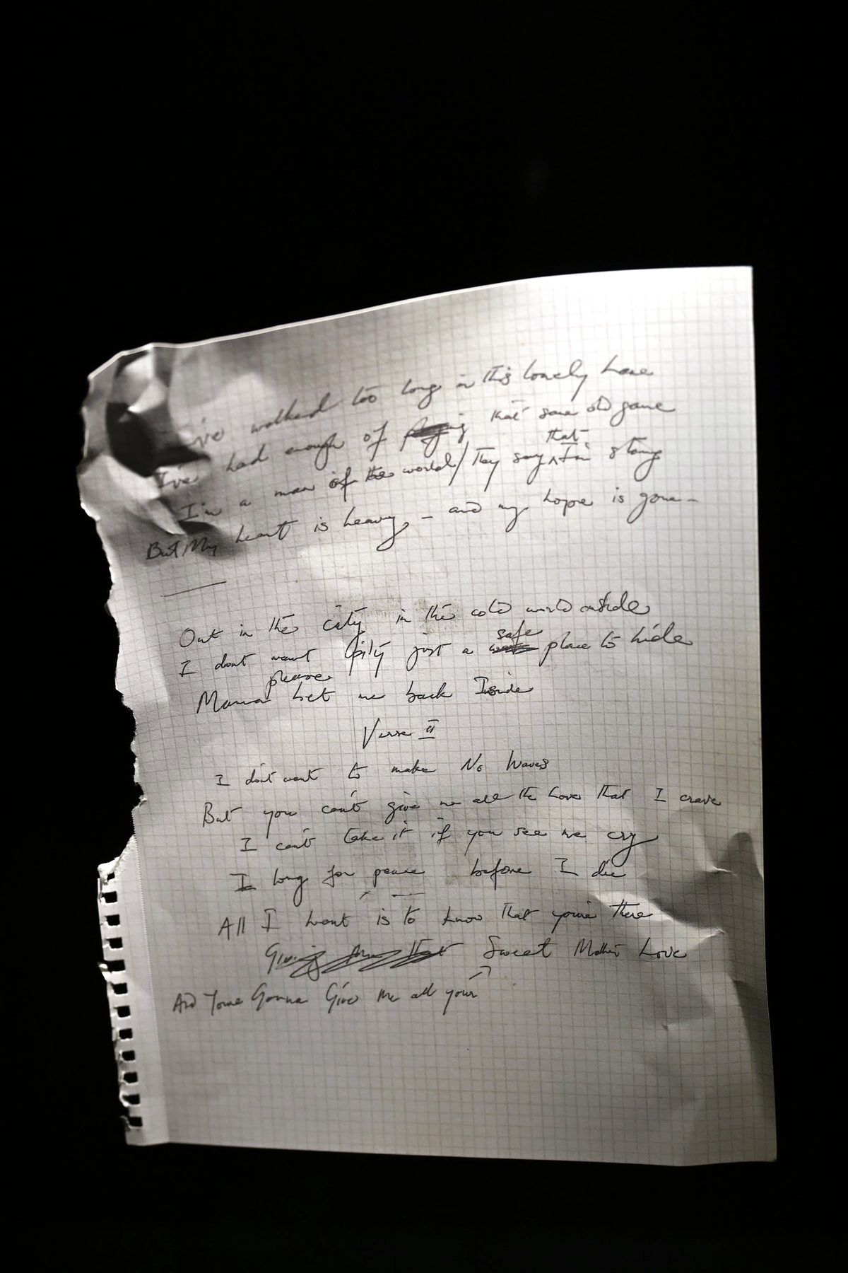 Folha de caderno com o rascunho manuscrito da letra de Mother Love exposta em vitrine