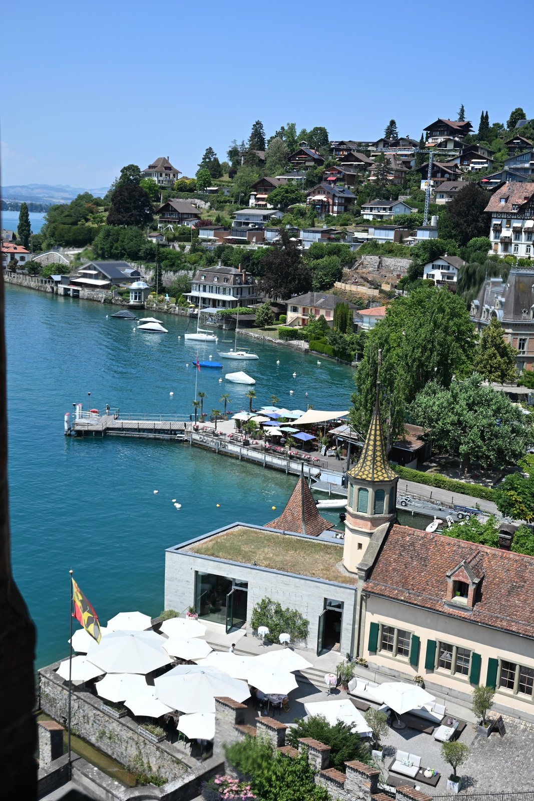 Bandeira do cantão de Berna sobre o píer e os barcos do Lago Thun, vistos do alto do Castelo de Oberhofen