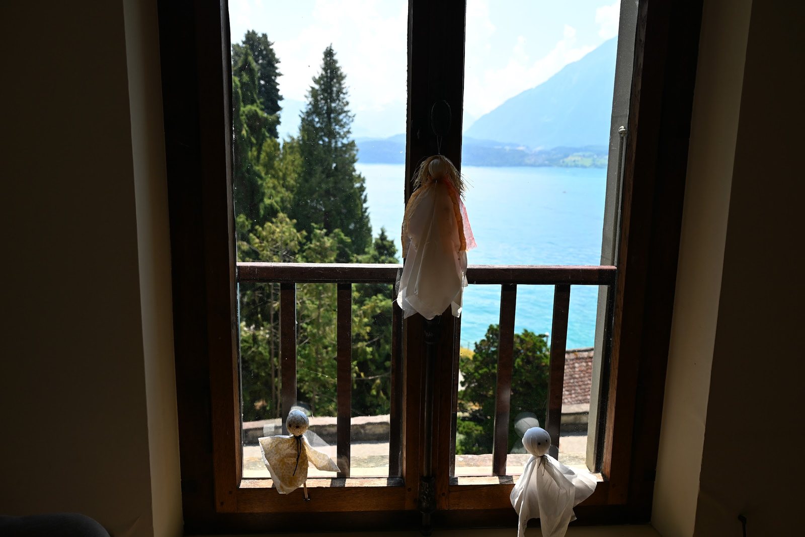 Fantasminhas de pano no peitoril de uma janela do Castelo de Oberhofen, com o Lago Thun ao fundo