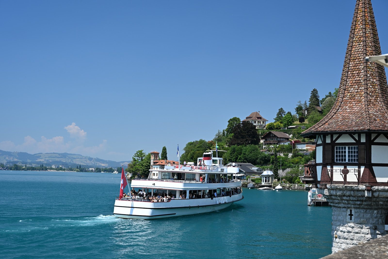 Barco do Lago Thun passando diante da torre de enxaimel do Castelo de Oberhofen