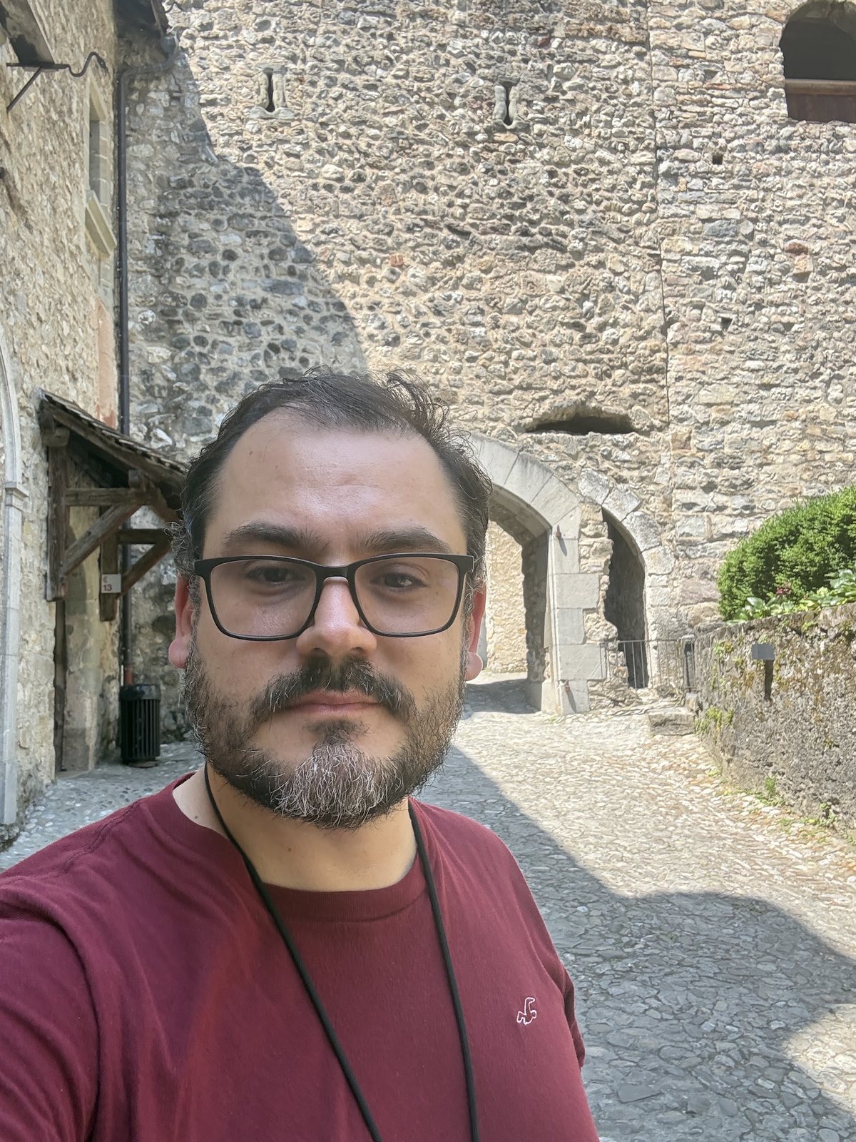 Raphael, da Viagem Suíça, no pátio do Castelo de Chillon, com duas seteiras visíveis na parede de pedra atrás dele