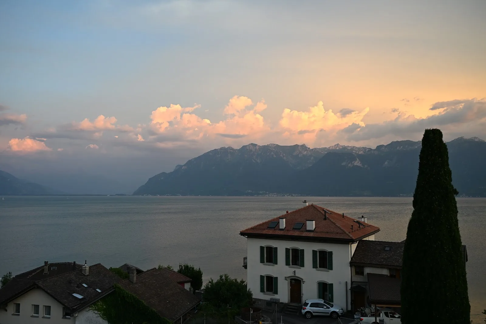 Nuvens iluminadas ao fim da tarde sobre as montanhas e o Lago Léman