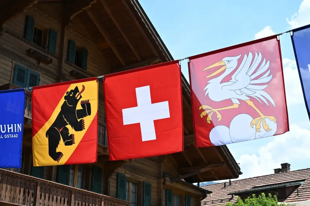 Bandeiras de Berna, da Suíça e de Saanen diante de um chalé em Gstaad